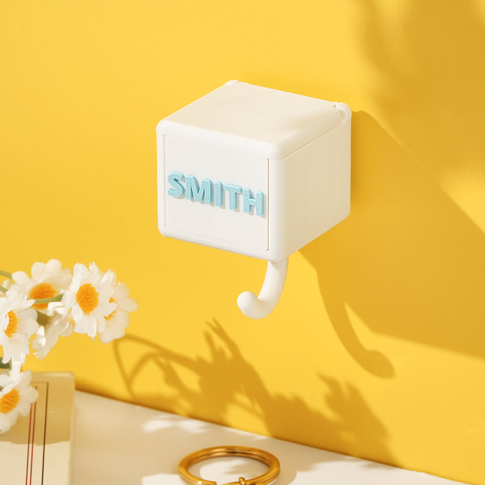 White 3D printed gravity hook with "SMITH" text, a PLA home decor gift on yellow wall
